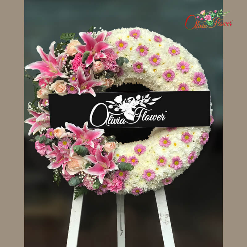 พวงหรีดดอกไม้สด ประกอบด้วย ลิลลี่สีชมพู 7 ดอก กุหลาบสีชมพู คาร์เนชั่นสีชมพู ดอกมัมสีขาว  และดอกมัมสีชมพู