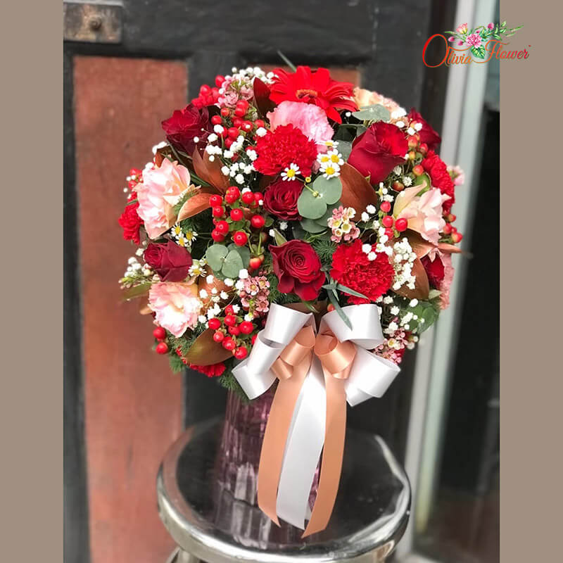 แจกันดอกไม้สด ประกอบด้วย กุหลาบสีชมพู คาร์เนชั่นสีแดง เยอบีร่าสีแดง ไลเซนทรัสสีพีช แว็ก มิกกี้เมาส์สีแดง ยิปซี และใบยูคา