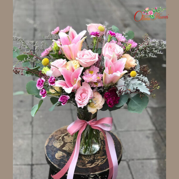 แจกันดอกไม้สด ประกอบด้วย กุหลาบสีชมพู ลิลลี่สีชมพู ไลเซนทรัสสีพีช มัมสีม่วง คาร์เนชั่นสีม่วง บอลทอง แคสเปีย และใบยูคา