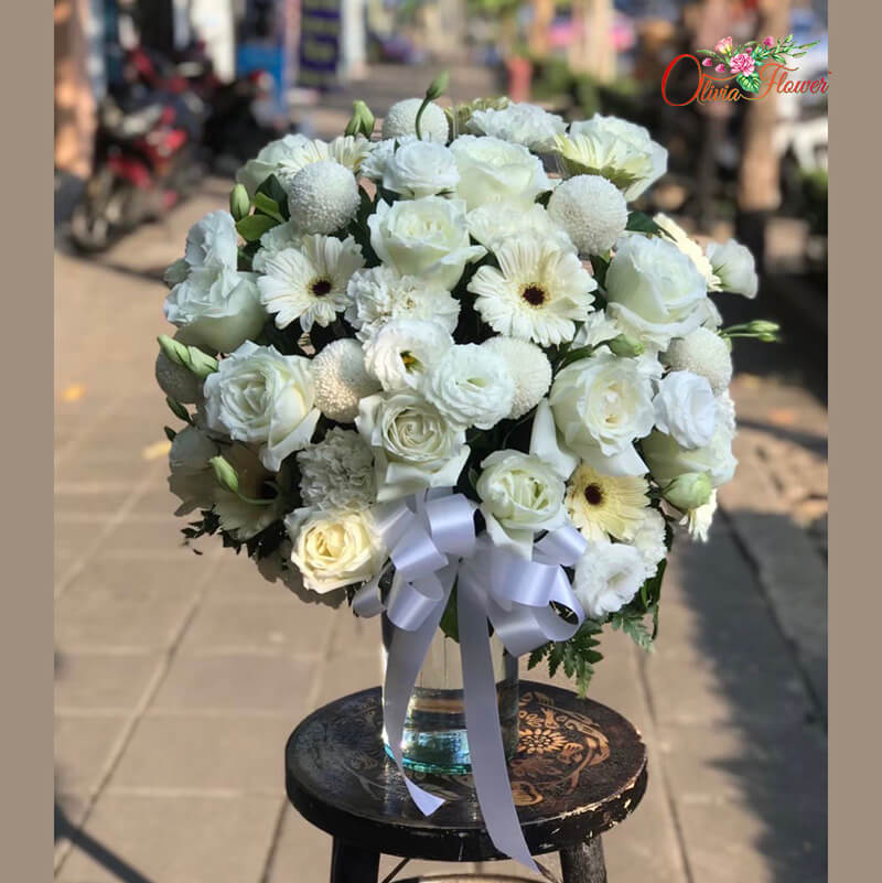 แจกันดอกไม้สด ประกอบด้วย กุหลาบสีขาว ปิงปองสีขาว คาร์เนชั่นสีขาว เยอบีร่าสีขาว และไลเซนทรัสสีขาว