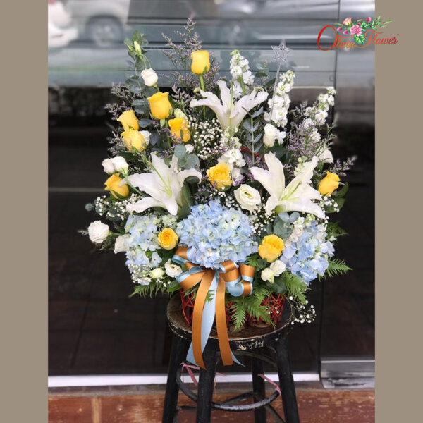 กระเช้าดอกไม้สด ประกอบด้วย กุหลาบสีเหลือง 10 ดอก ลิลลี่สีขาว สต็อคสีขาว ไฮเดรนเยียสีฟ้า ไลเซ็นทรัสสีขาว ยูคา แคสเปีย และยิปซี
