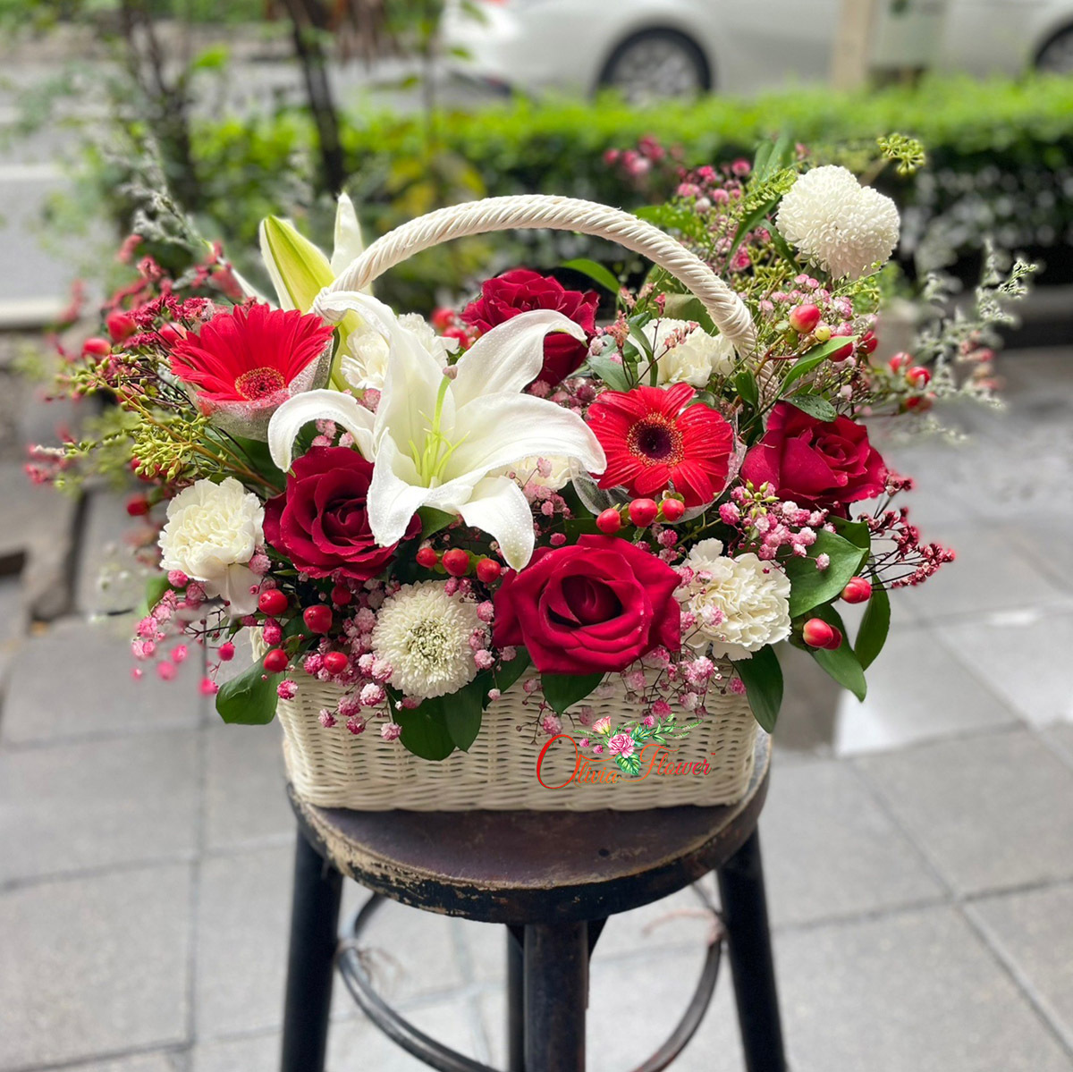 กระเช้าดอกไม้สด ประกอบด้วย ดอกกุหลาบสีแดง 4 ดอก ดอกปิงปอง 2 ดอก ดอกคาร์เนชั่นสีขาว ดอกมิกกี้เมาส์ ดอกลิลลี่ 2 ดอก และดอกยิปซี